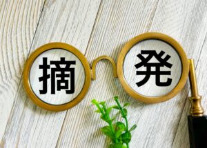 摘発という文字をメガネのような道具で強調してる写真